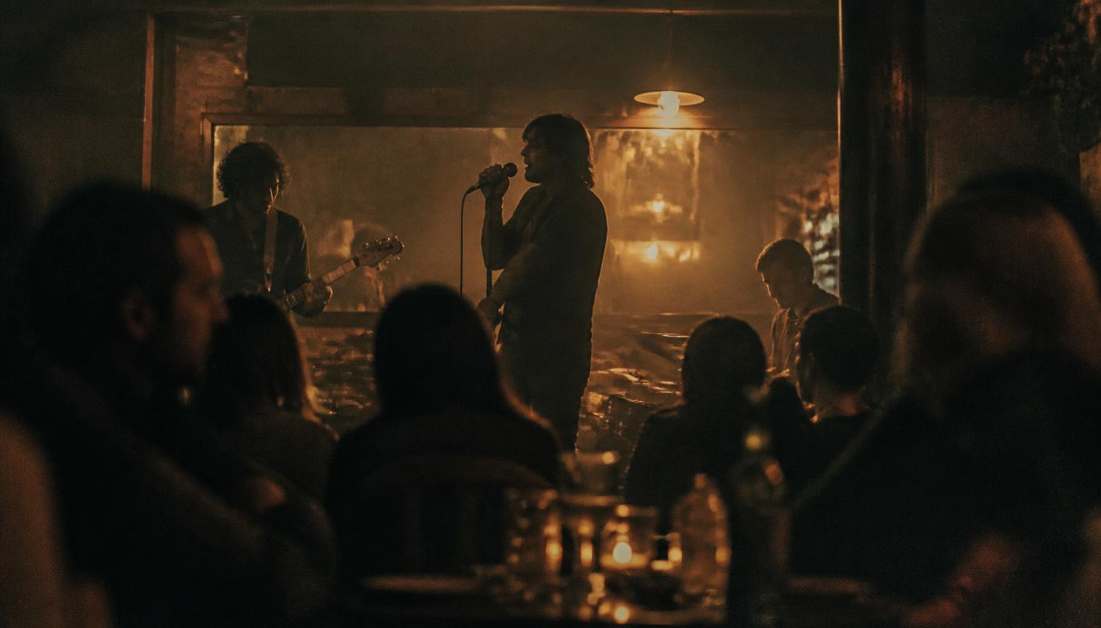 Live band silhouetted in warm amber light in a dark, intimate room